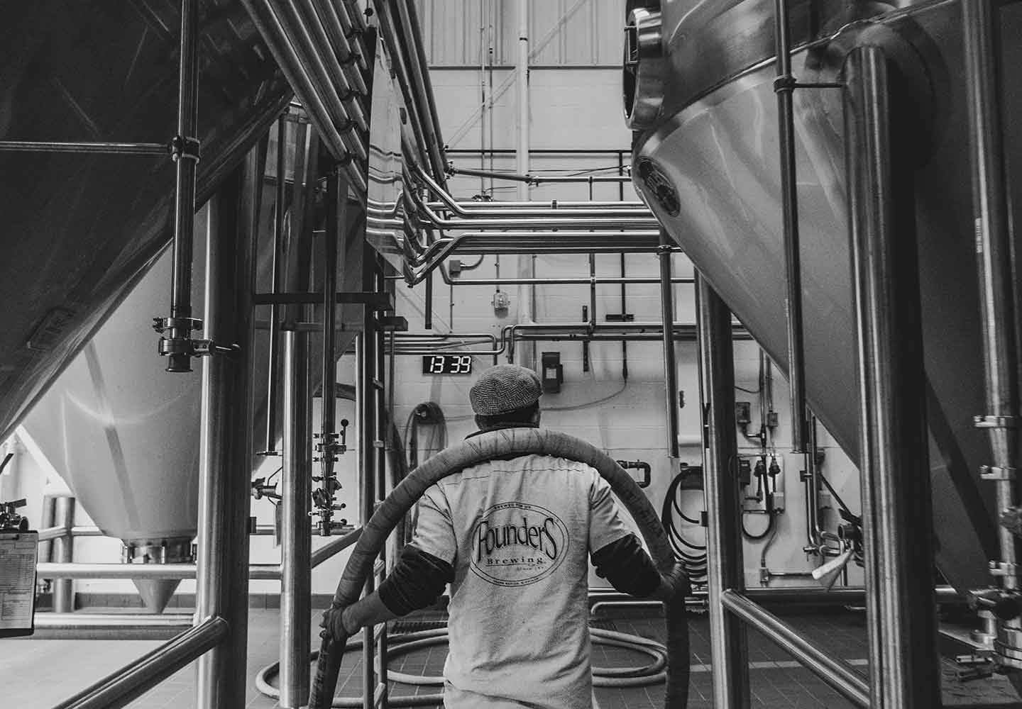 Black and white image of employee carrying a hose on their back in Barrel House