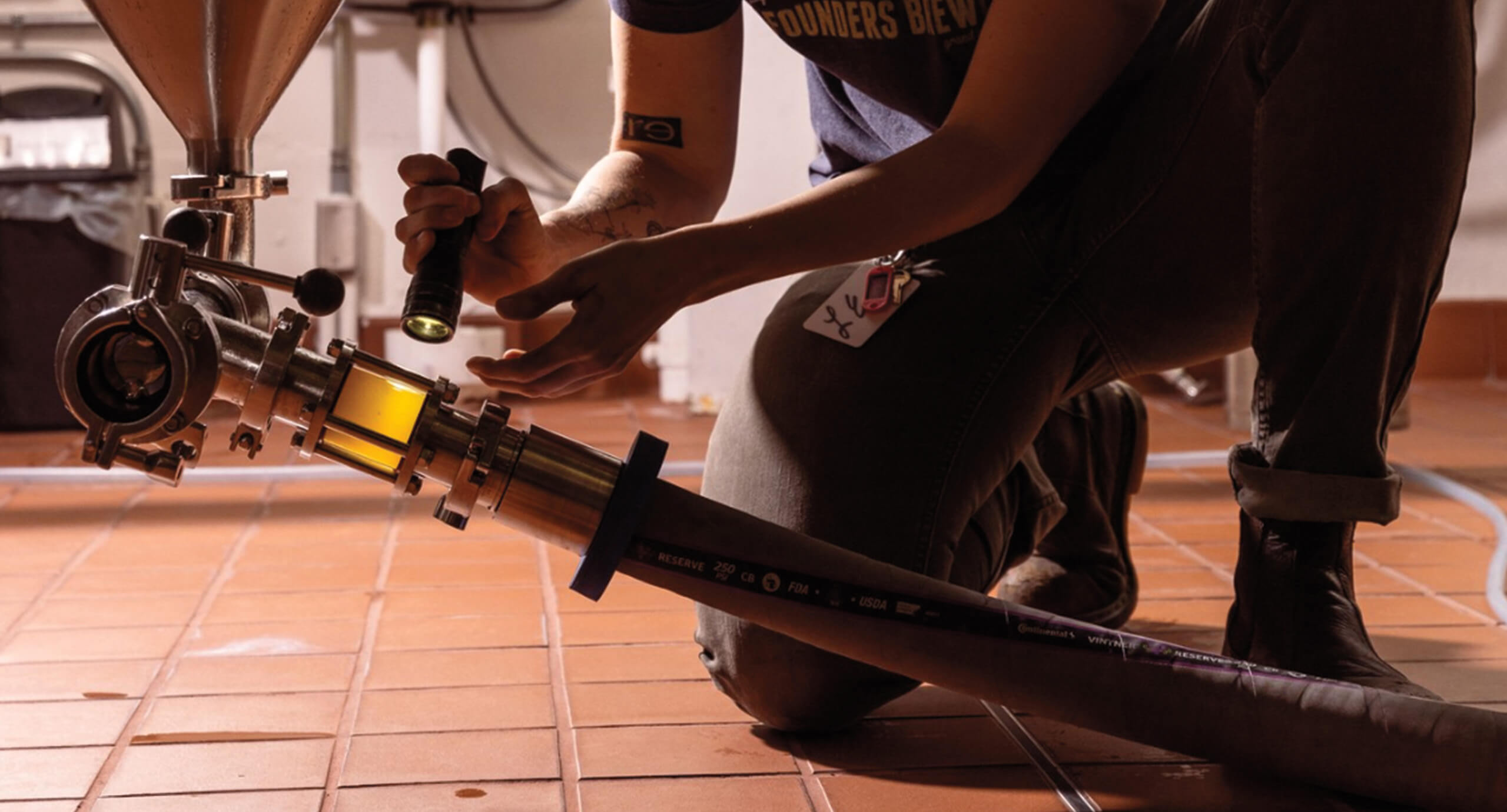 Employee inspecting a hose with beer in it in the brewery