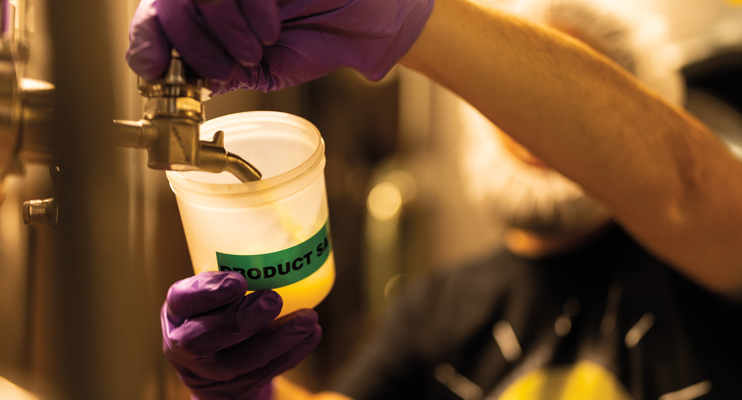 Person pouring something into a plastic container in the brewery