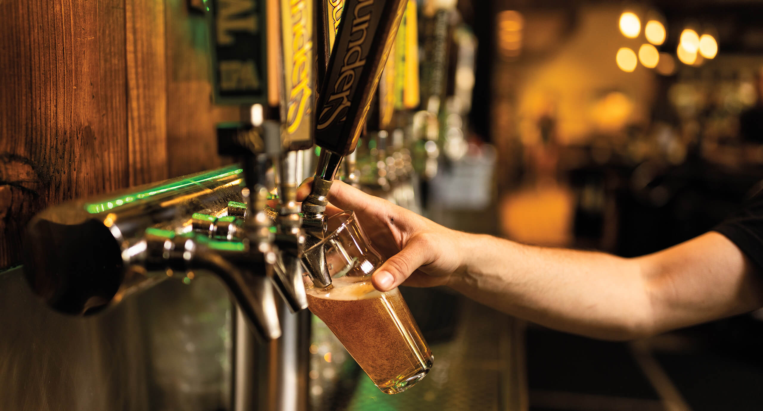 Founders bartender filling a pint glass with a tap