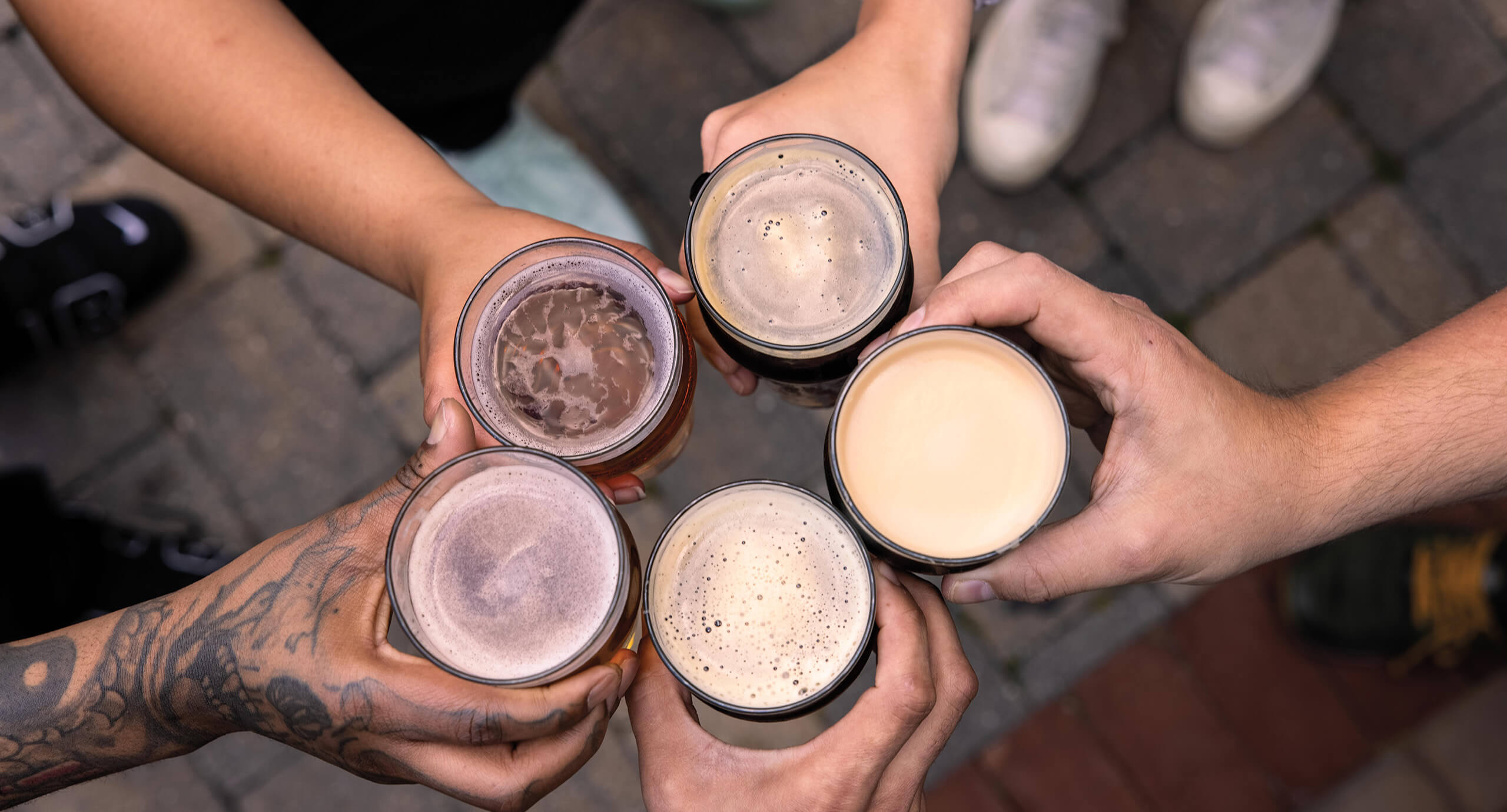 Overhead shot of multiple glasses of beer meeting in a circle