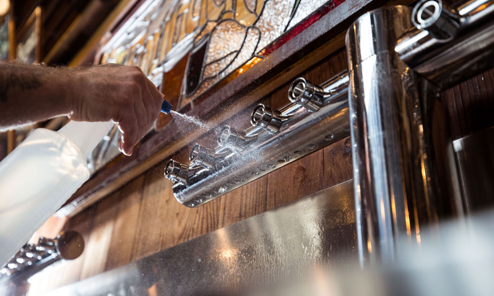 Man spraying water on draft lines at Founders Brewing Co.
