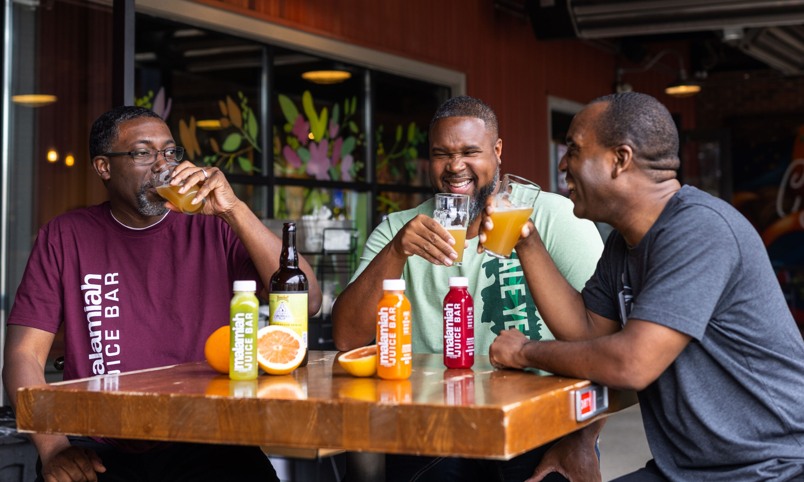 Malamiah Juice owners sitting at table drinking beer with fruit on table